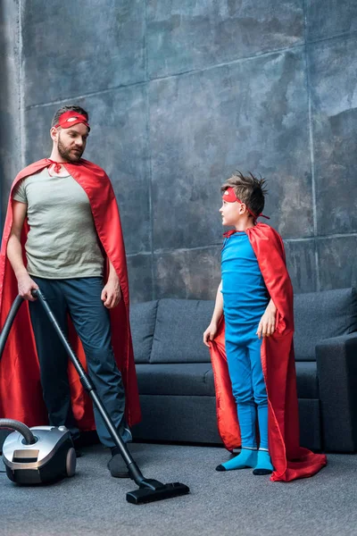 父亲和儿子在超级英雄服装用真空吸尘器清理 — 图库照片