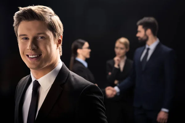 Businessman smiling on foreground — Stock Photo, Image