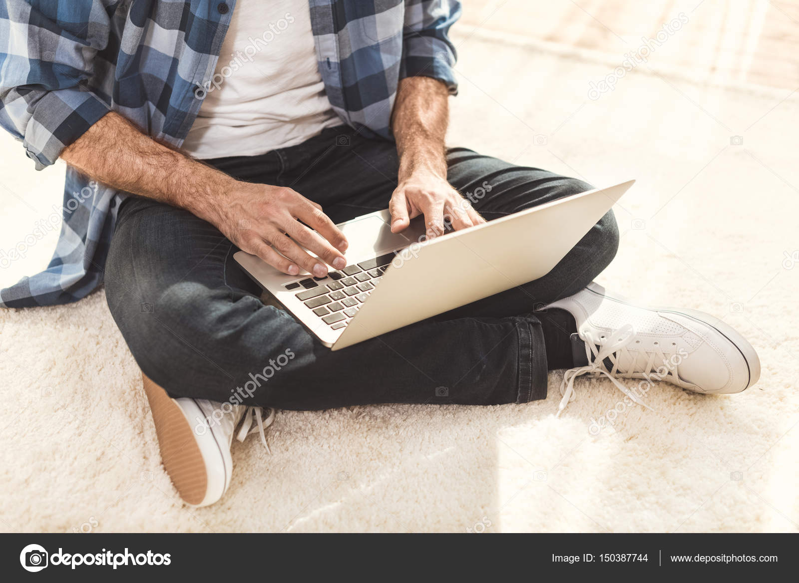 Man sitting on carpet and typing on laptop — Stock Photo