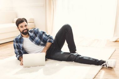 man lying on carpet and using laptop clipart