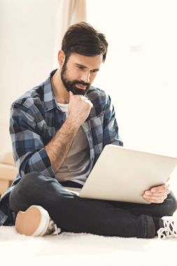 Thoughtful man looking at laptop monitor clipart