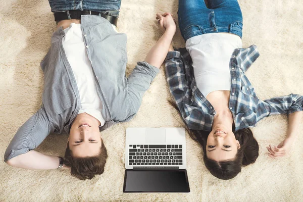 Paar liggen op tapijt tussen laptop — Stockfoto