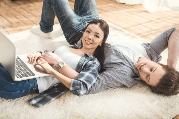 Woman lying on boyfriend and using laptop — Stock Photo, Image