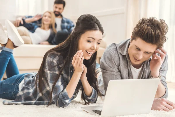 Casal deitado no tapete e usando laptop — Fotografia de Stock