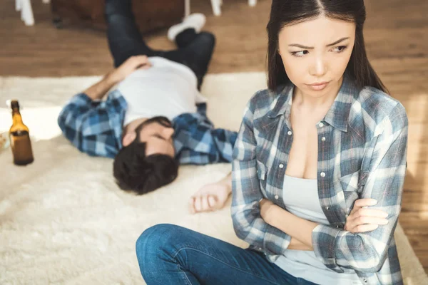 Woman sitting on floor near drunk boyfriend — Stock Photo, Image