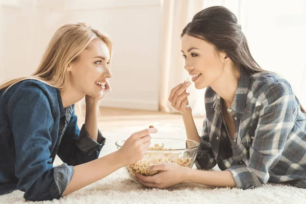 Wanita berbaring di karpet dan makan popcorn — Stok Foto