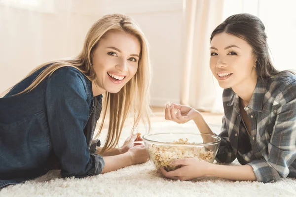 Kvinnor liggande på matta och äta popcorn — Stockfoto