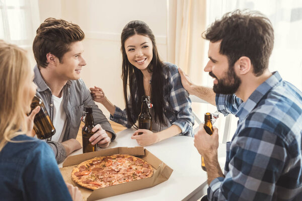 couples drinking beer and eating pizza