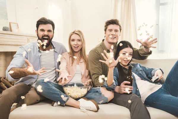 Persone sul divano gettando popcorn a testa in giù — Foto Stock