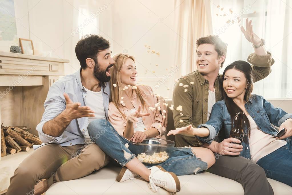 People on couch throwing popcorn upside — Stock Photo