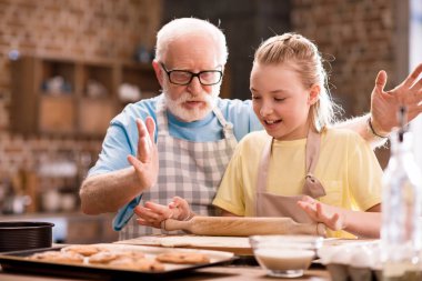 grandfather and granddaughter kneading dough  clipart