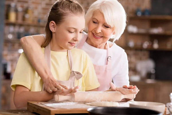 Grand-mère et petit-enfant pétrissant la pâte — Photo