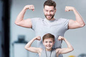 Chlapec s mladým mužem, ukazuje svaly 