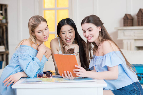 women holding digital tablet while sitting