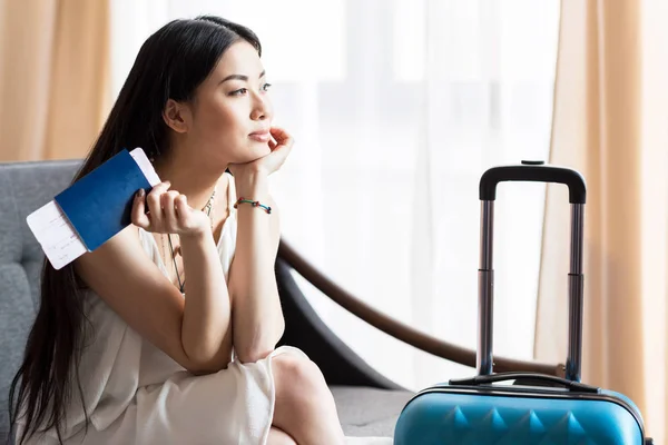 Asiatin sitzt mit Koffer — Stockfoto