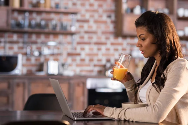 Woman having breakfast and using laptop — Stock Photo, Image