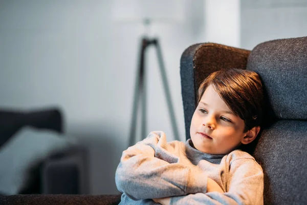 Pojken sitter i fåtölj — Stockfoto