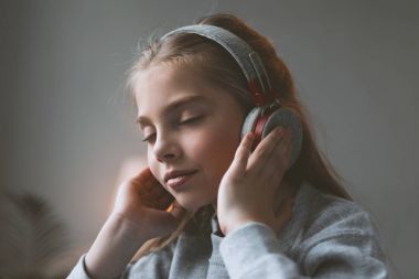 kid girl listening music in headphones clipart