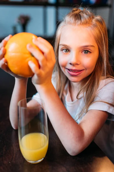 Χαμογελαστό κορίτσι παιδί κρατώντας πορτοκαλί — Φωτογραφία Αρχείου