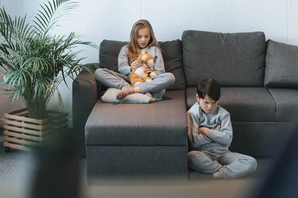 Mädchen mit Teddybär und Junge sitzend — Stockfoto