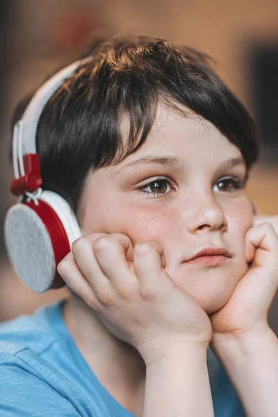 Застенчивый мальчик слушает музыку в наушниках — стоковое фото