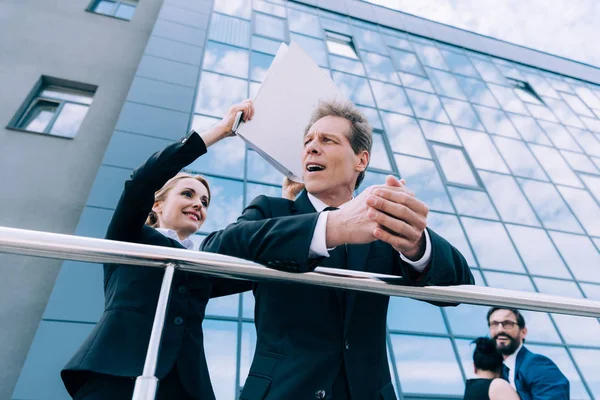 Businesswoman with folder hitting businessman — Free Stock Photo