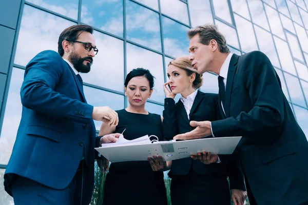 Kağıtları tartışırken çok ırklı iş adamları 