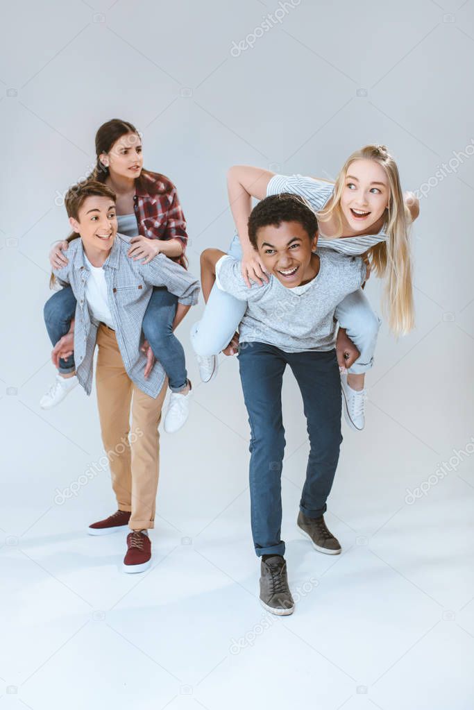 multicultural teenagers piggybacking together