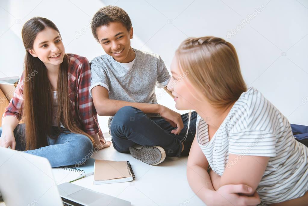 multiethnic smiling teenagers with laptop