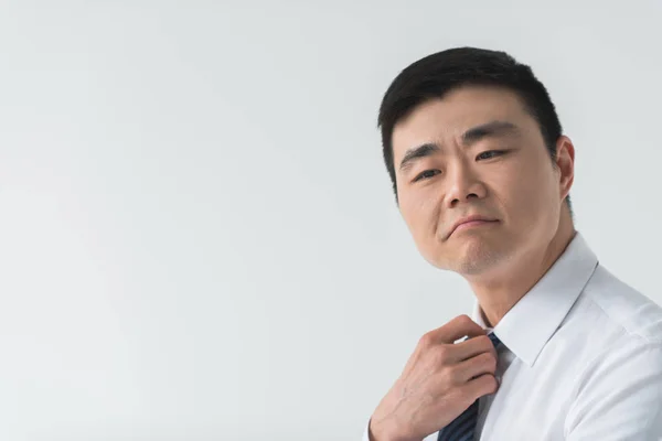 Asian businessman tying necktie — Free Stock Photo