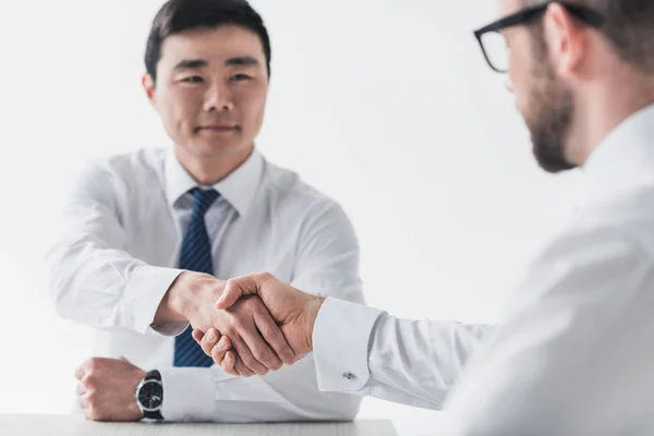 Мультикультурные бизнесмены пожимают друг другу руки на встрече — стоковое фото