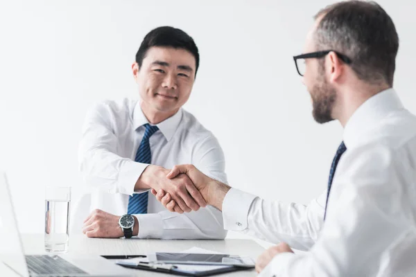 Hombres de negocios multiculturales estrechando la mano en la reunión — Foto de Stock