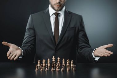 businessman sitting at table with chess pieces