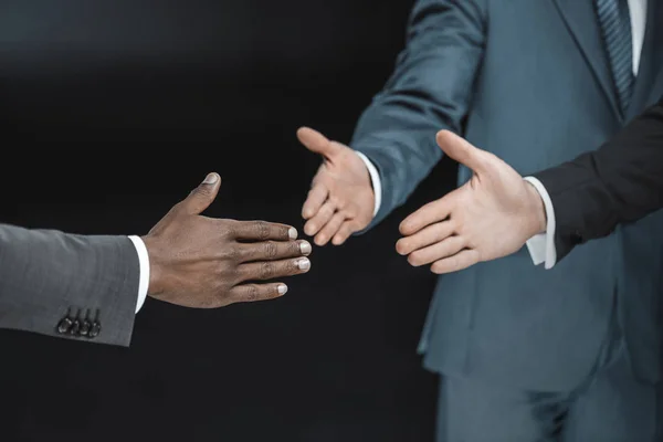 Multiethnic businessmen outstretching hands — Stock Photo, Image