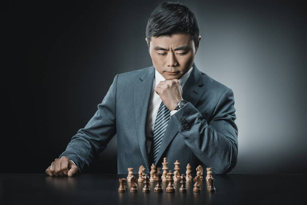 азиатский бизнесмен и шахматные фигуры
