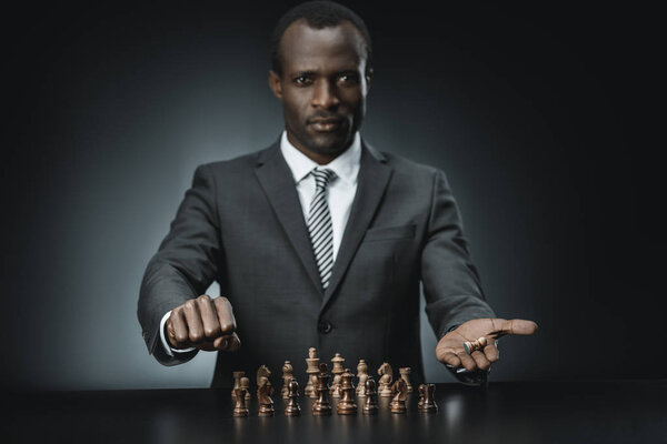 Африканский бизнесмен, держащий в руках шахматную фигуру
