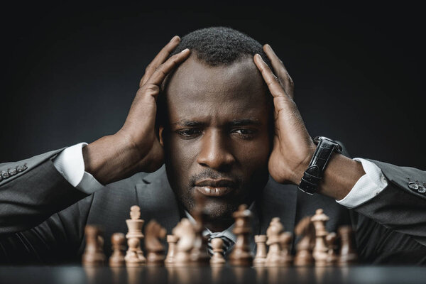 confused african american businessman with chess