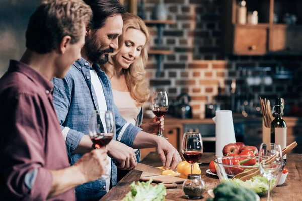 Amigos bebendo vinho enquanto cozinha o jantar — Fotografia de Stock