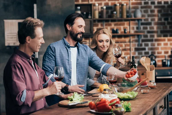 Friends drinking wine while cooking dinner — Stock Photo, Image