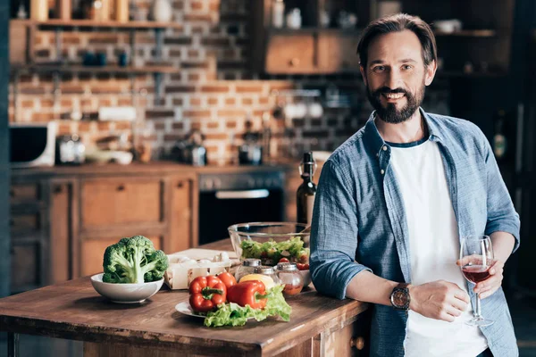 Uomo che beve vino in cucina — Foto Stock