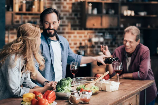 Amigos bebendo vinho enquanto cozinha o jantar — Fotografia de Stock