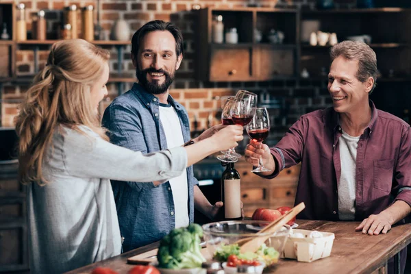 Amigos bebendo vinho enquanto cozinha o jantar — Fotografia de Stock