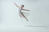 elegantní baletka v bílých šatech jumping Studio, izolované na bílém