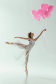 Ballerina im weißen Kleid tanzt mit rosa Luftballons, isoliert auf weiß