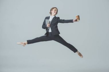 businesswoman in suit and ballet shoes jumping with coffee and tablet, isolated on grey clipart