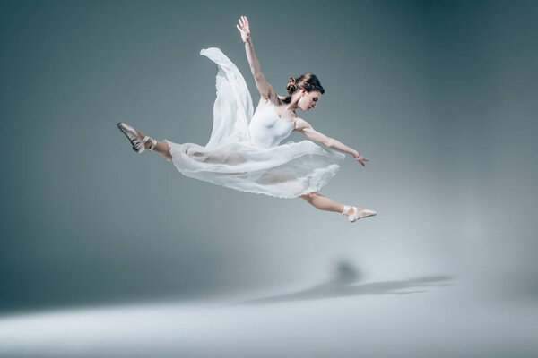 elegant ballet dancer jumping in white dress