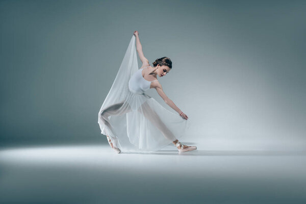 elegant beautiful ballerina dancing in white dress