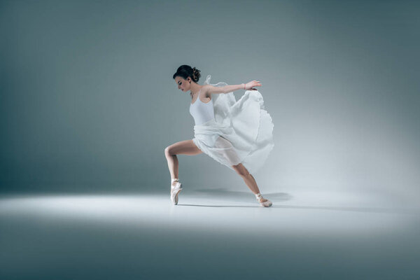 элегантная балерина танцует в белом платье
