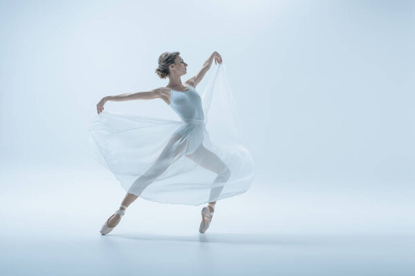 elegant ballerina in white dress dancing in studio, isolated on white
