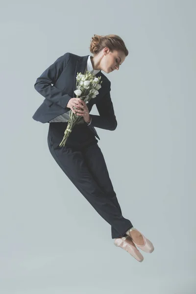 グレーに分離された花の花束とジャンプ スーツとバレエ シューズの女性実業家 ストック画像